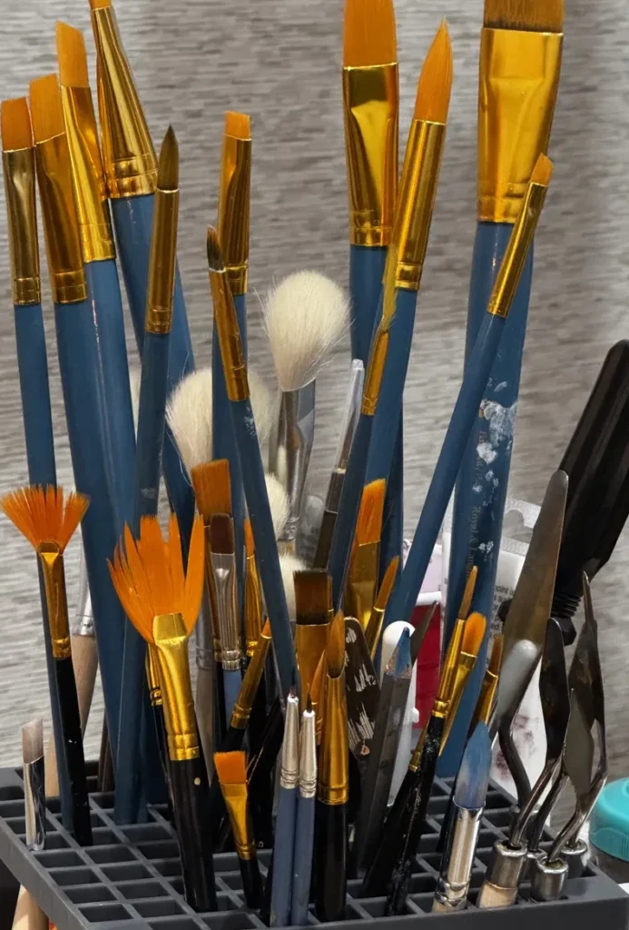 Well-used paintbrushes and palette knives in Hemakshi Valera's studio, where each free original mini is hand-painted